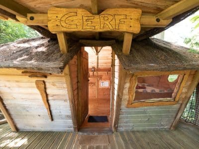 Cabane dans les arbres en Auvergne-Rhône-Alpes, avec un toit en chaume et une entrée accueillante.