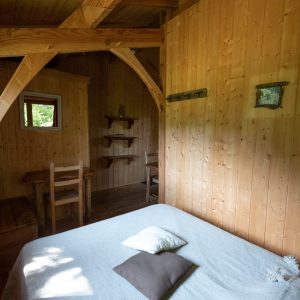 Cabane en bois cosy avec un lit douillet et des murs en bois clair.