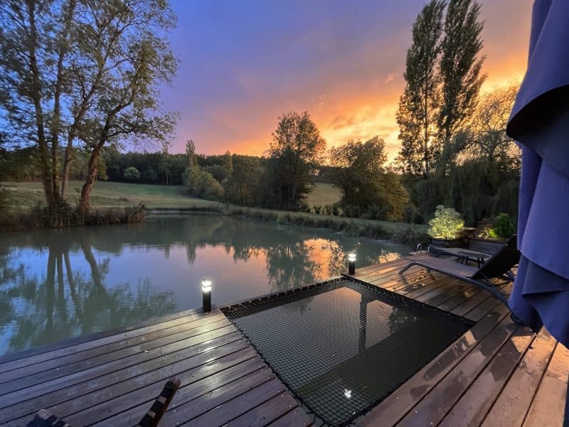 Chalet au bord de leau, avec une terrasse en bois et un coucher de soleil apaisant.