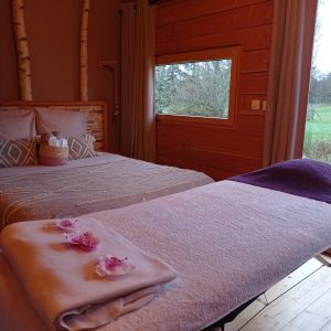 Hébergement insolite en bois avec lit douillet et vue sur la nature verdoyante.