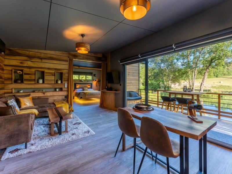 Chalet moderne avec vue sur la nature, salon cosy et espace repas lumineux.