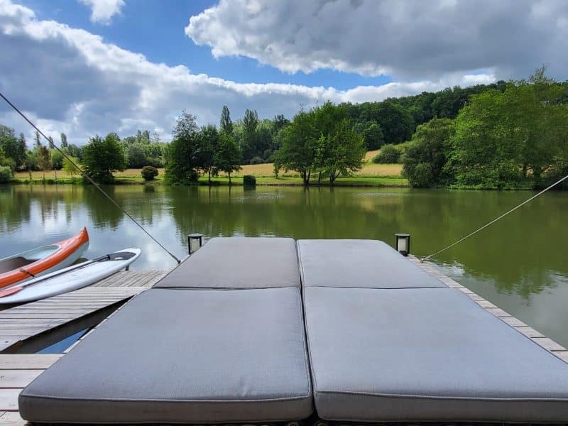 Chalet au bord dun lac, avec un ponton et des canoës colorés.