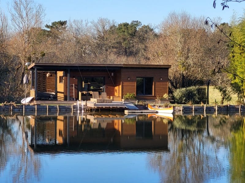 Chalet en bois au bord dun lac, avec une terrasse et des kayaks.