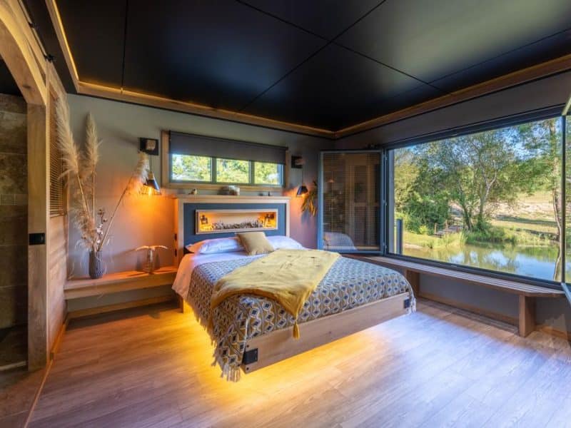 Chambre moderne avec vue sur la nature, lit confortable et décoration élégante.