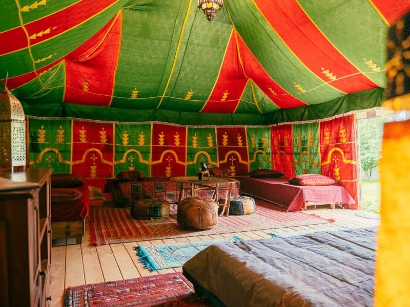 Tente berbère colorée avec tapis et coussins, offrant une ambiance chaleureuse et accueillante.