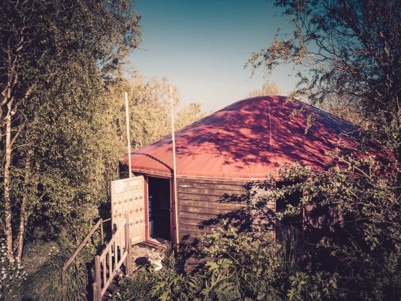 Yourte colorée avec un toit rouge, entourée de verdure en Basse-Normandie.