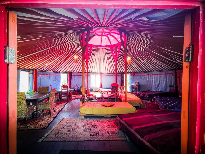Yourte colorée avec un intérieur chaleureux, lit confortable et mobilier en bois.