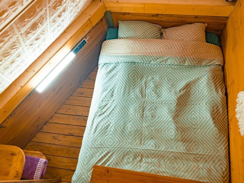 Chalet cosy avec lit double, draps à motifs géométriques et ambiance chaleureuse.