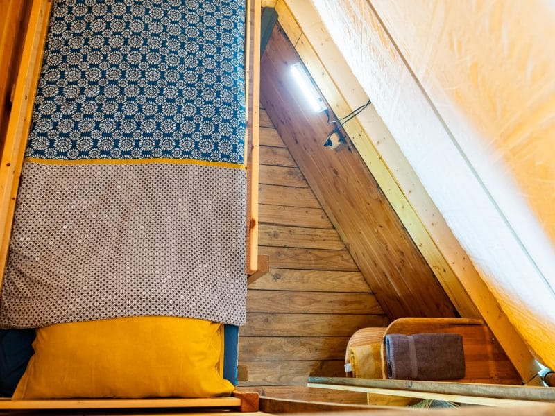 Chambre en mezzanine cosy avec lit douillet et murs en bois chaleureux.