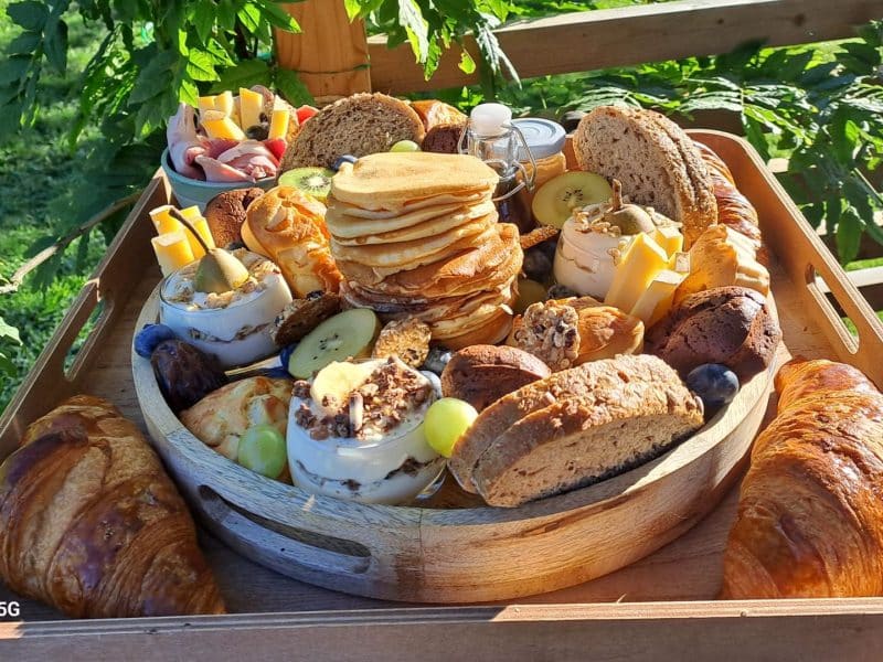 Plateau de petit-déjeuner dans un gîte, avec pancakes, fruits et viennoiseries.
