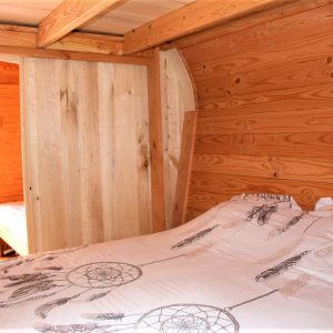 Cabane en bois avec lit douillet et décoration de plumes, ambiance chaleureuse.