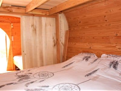 Cabane en bois avec lit douillet et décoration de plumes, ambiance chaleureuse.