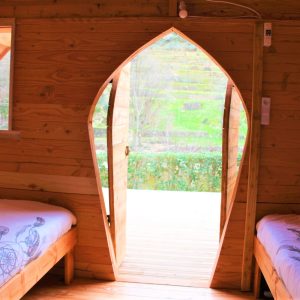 Cabane en bois avec porte en forme darc, vue sur la nature verdoyante.