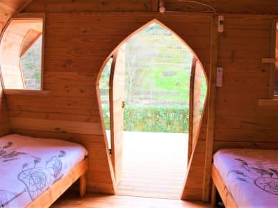 Cabane en bois avec porte en forme darc, vue sur la nature verdoyante.