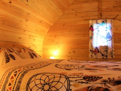 Chalet en bois chaleureux avec lit douillet et rideaux colorés. Parfait pour un séjour unique.
