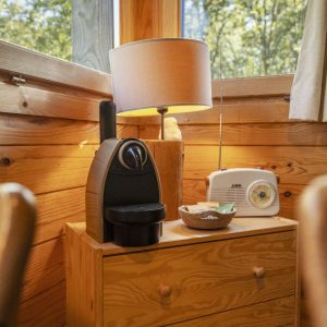 Hébergement insolite en bois avec une lampe et une machine à café dans un cadre naturel.