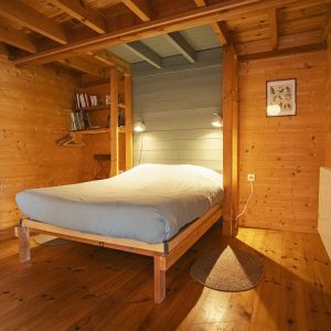 Chalet en bois chaleureux avec lit confortable et ambiance naturelle.