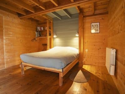 Chalet en bois chaleureux avec lit confortable et ambiance naturelle.