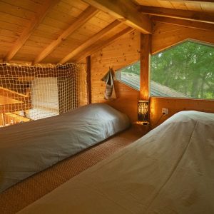 Chalet en bois avec vue sur la nature, lits simples et ambiance chaleureuse.