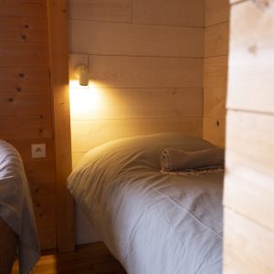 Chalet en bois chaleureux avec lit douillet et éclairage doux.