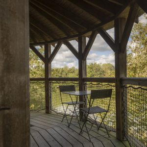 Cabane perchée en bois avec terrasse et vue sur la nature environnante.