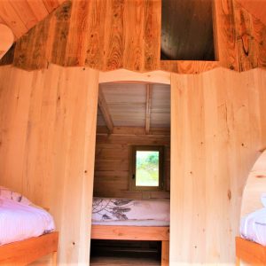 Intérieur dune cabane en bois avec lits jumeaux et lumière naturelle.