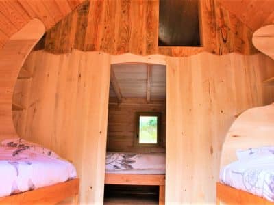 Intérieur dune cabane en bois avec lits jumeaux et lumière naturelle.