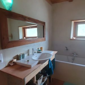 Salle de bain dun hébergement insolite en bois, avec baignoire et lumière douce.