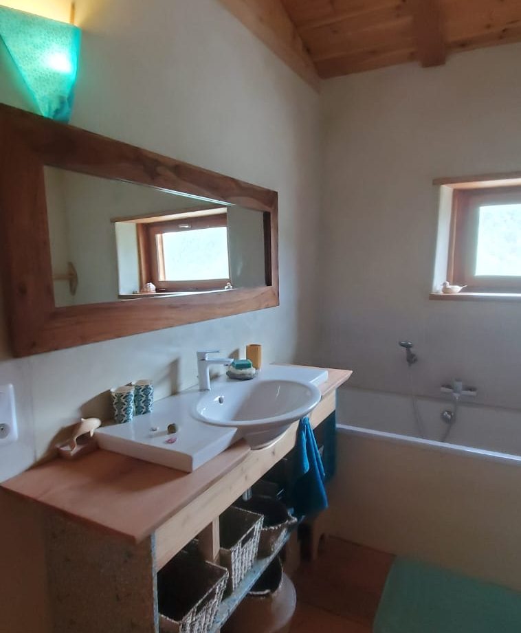 Salle de bain dun hébergement insolite en bois, avec baignoire et lumière douce.
