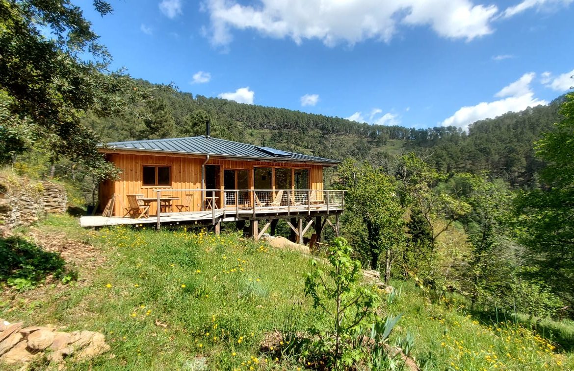 Cabane en bois avec terrasse, nichée dans la verdure du Languedoc-Roussillon.
