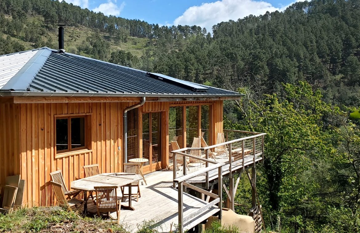 Cabane en bois avec terrasse, entourée de verdure dans le Languedoc-Roussillon.