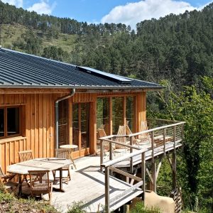 Cabane en bois avec terrasse, entourée de verdure dans le Languedoc-Roussillon.