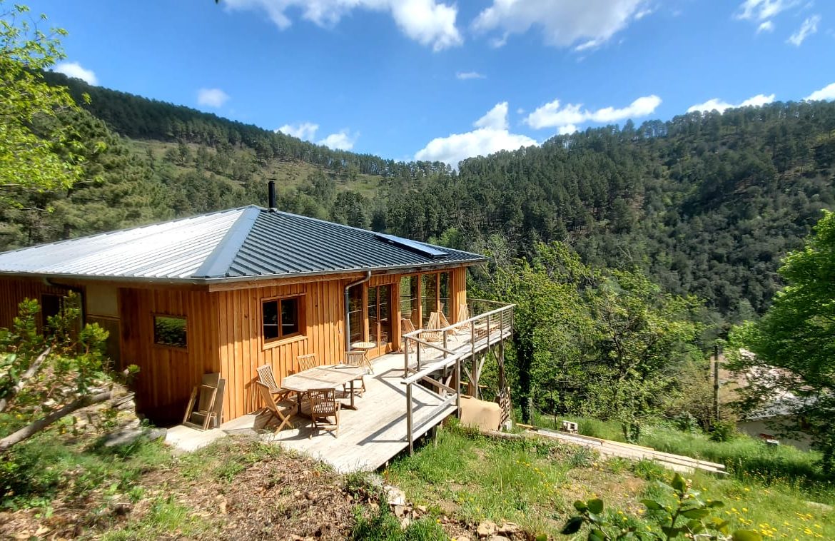 Chalet en bois avec terrasse, niché dans la verdure du Languedoc-Roussillon.