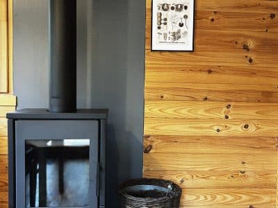 Hébergement insolite en Pays de la Loire avec poêle à bois et murs en bois chaleureux.