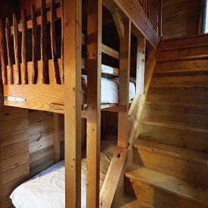 Cabane en bois avec lits superposés et escalier en bois chaleureux.