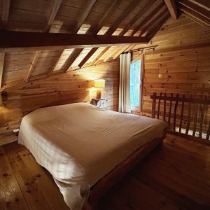 Chalet en bois chaleureux avec lit king-size et lumière douce.