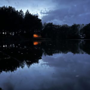 Cabane sur pilotis au bord dun lac, illuminée sous un ciel nocturne.