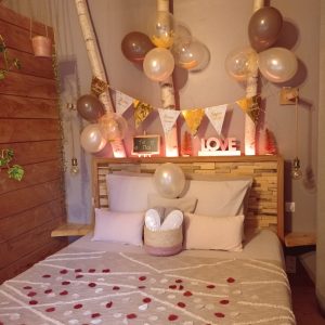 Chalet romantique avec décor festif, lit douillet et ballons colorés.