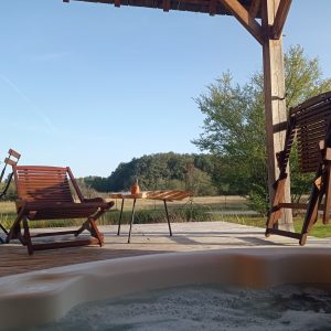 Hébergement insolite en bois avec jacuzzi, vue sur la nature verdoyante.