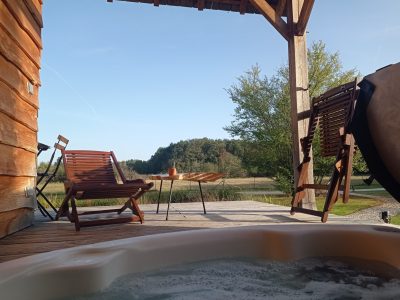 Hébergement insolite en bois avec jacuzzi, vue sur la nature verdoyante.