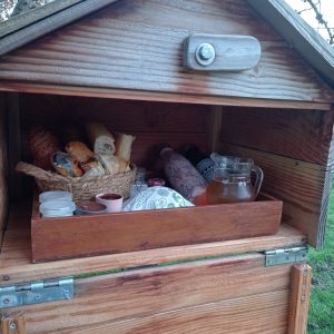 Hébergement insolite en cabane avec un panier de viennoiseries et boissons.