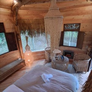 Cabane en bois cosy avec lit douillet et décoration naturelle, au cœur de la nature.