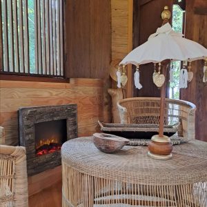 Hébergement insolite en Pays de la Loire : intérieur en bois avec cheminée et mobilier en rotin.
