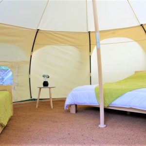 Tente géodésique spacieuse avec lits confortables et décoration naturelle.