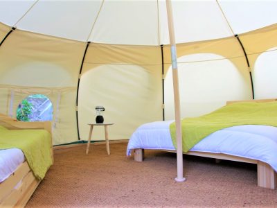 Tente géodésique spacieuse avec lits confortables et décoration naturelle.