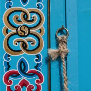 Cabane colorée en bois avec motifs artistiques et une corde en jute.