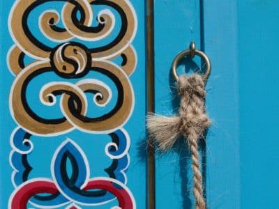 Cabane colorée en bois avec motifs artistiques et une corde en jute.