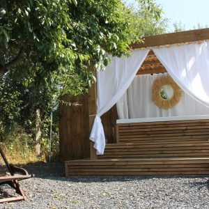 Hébergement insolite en bois avec un espace détente et des rideaux blancs.