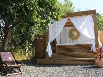 Hébergement insolite en bois avec un espace détente et des rideaux blancs.