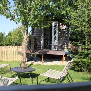 Cabane perchée dans le jardin, entourée darbres et de chaises confortables.